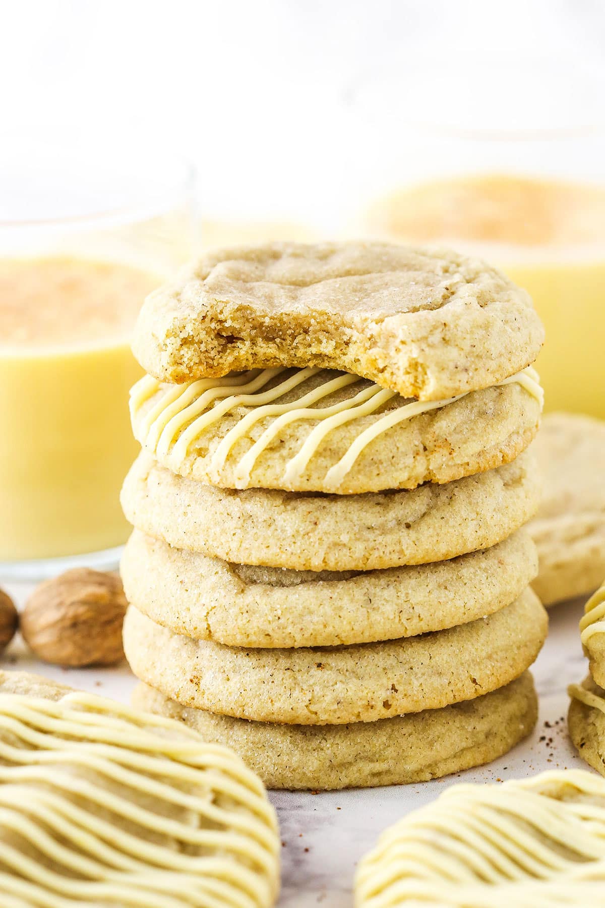 Six Eggnog Cookies stacked with the top cookie missing a bite.