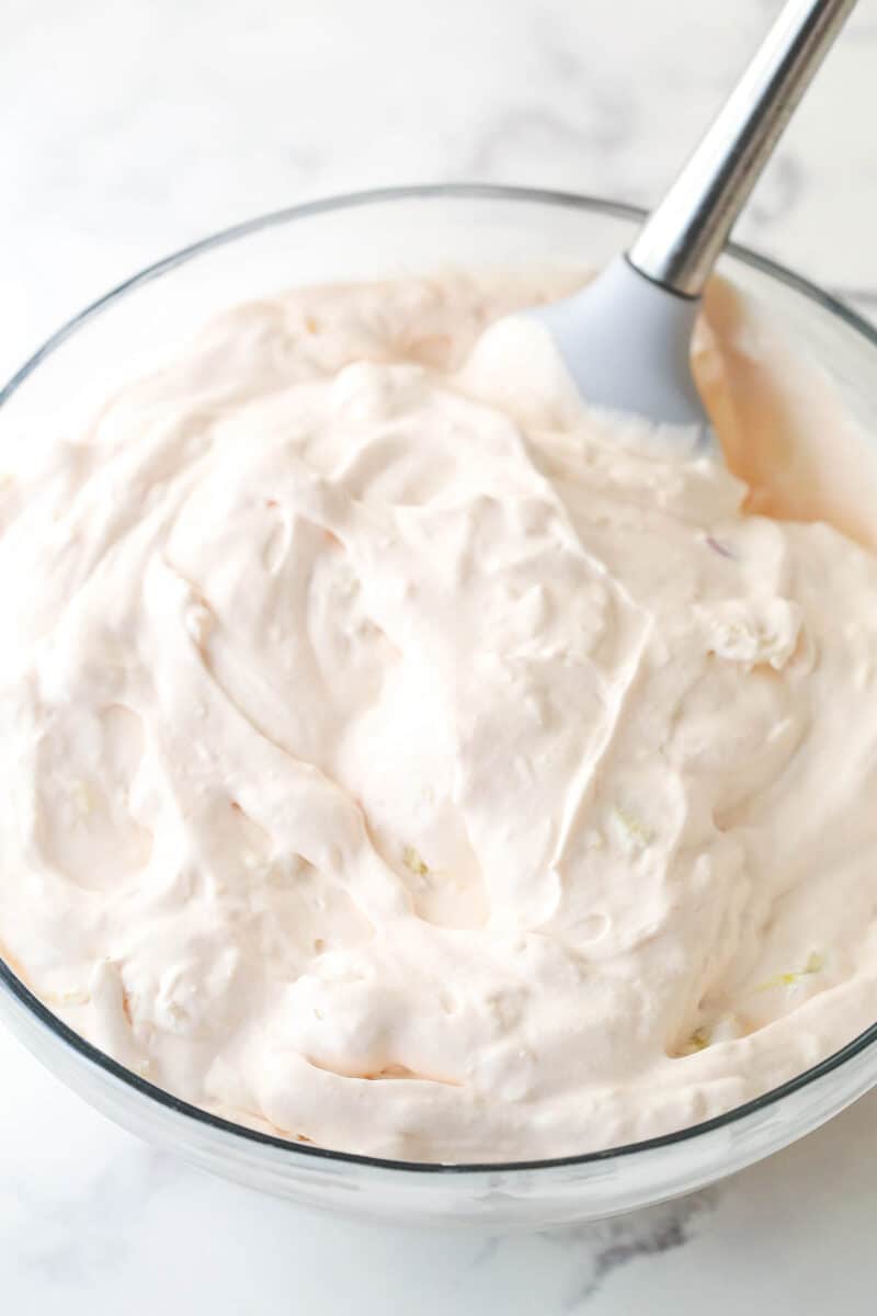 Folding fruit into a Cool Whip mixture.