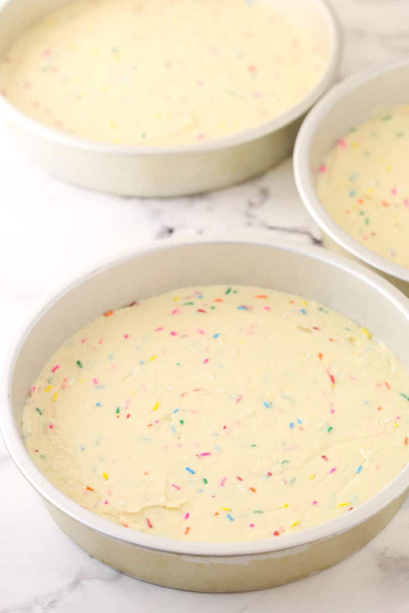 Funfetti cake batter divided between 3 cake pans.