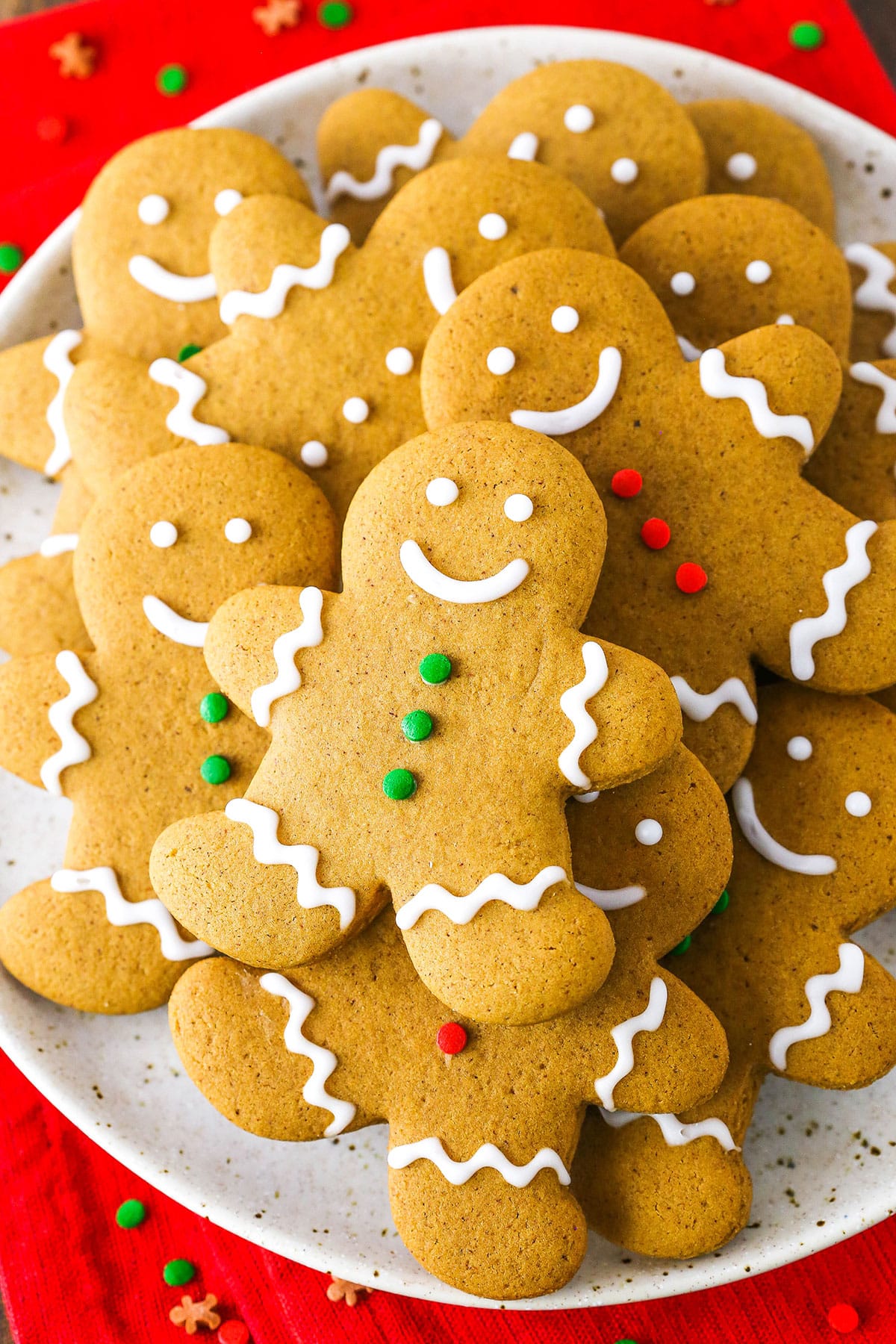 Gingerbread Cookies decorated with white, green and red frosting layered on a white plate