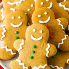 Gingerbread Cookies decorated with white, green and red frosting layered on a white plate