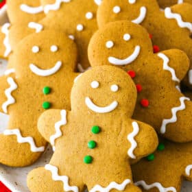 Gingerbread Cookies decorated with white, green and red frosting layered on a white plate