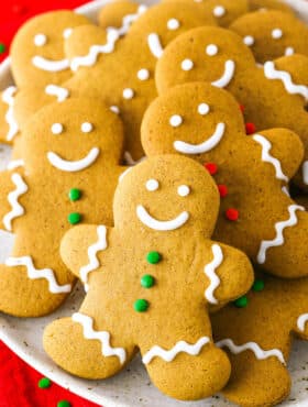 Gingerbread Cookies decorated with white, green and red frosting layered on a white plate