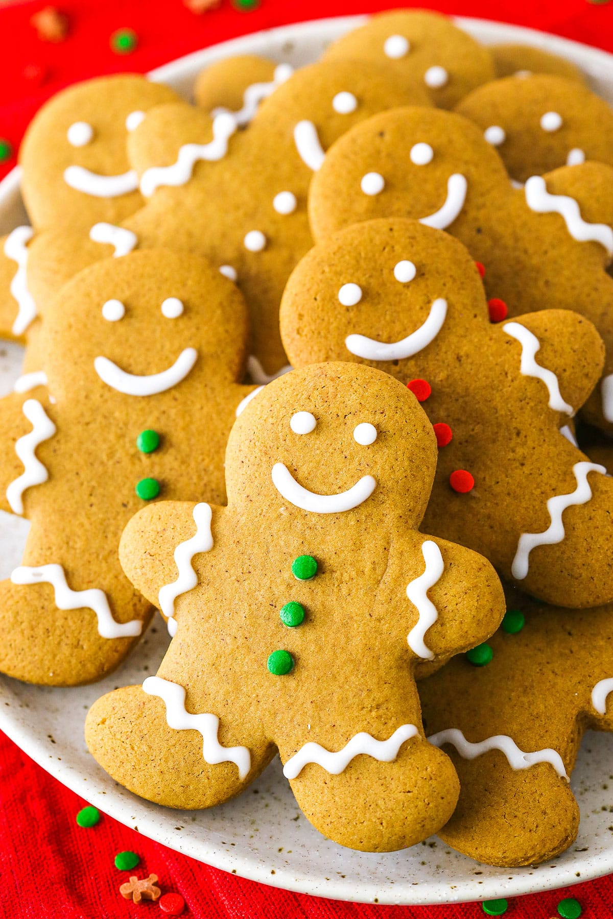 Gingerbread Cookies decorated with white, green and red frosting layered on a white plate