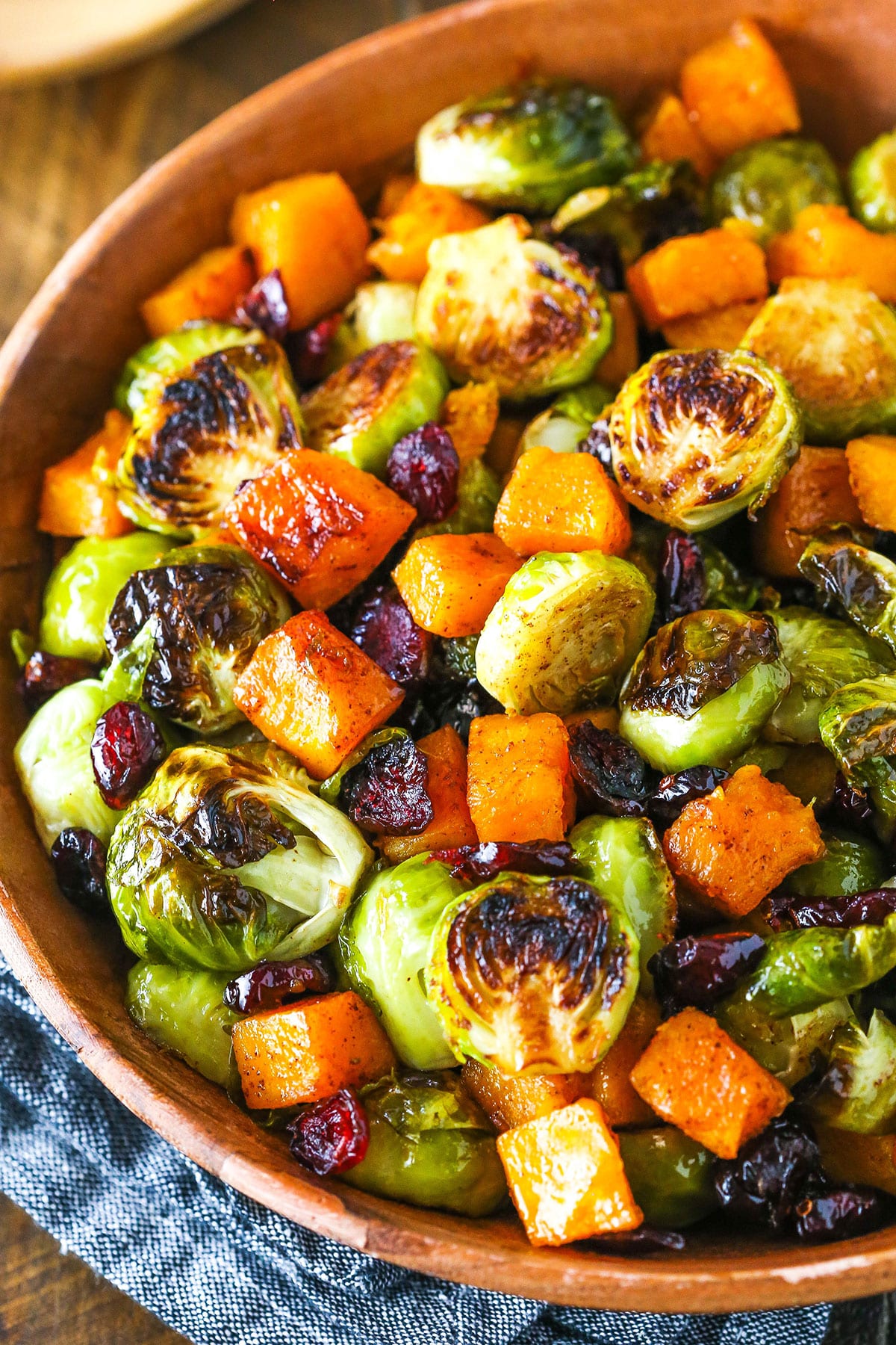 Honey Roasted Brussels Sprouts with Butternut Squash and Cranberries in a wooden serving dish