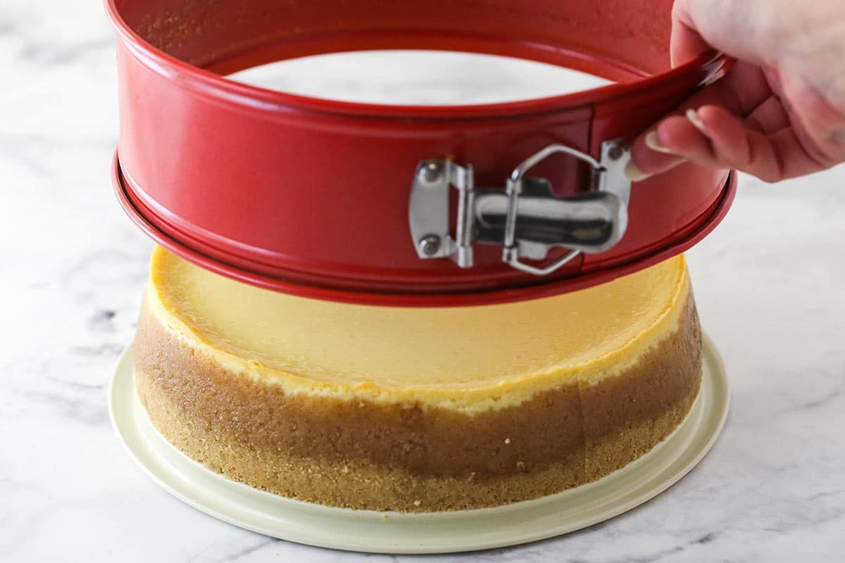 the sides of the springform pan being lifted off of the cheesecake