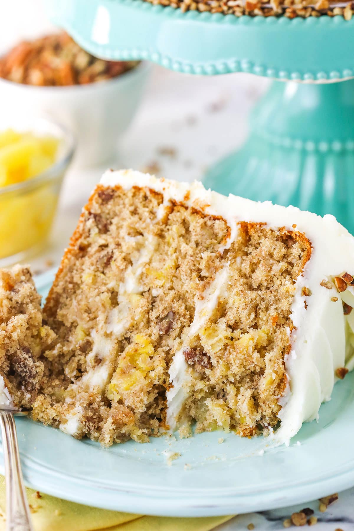 A slice of Hummingbird Cake with a bite taken out next to a fork on a blue plate