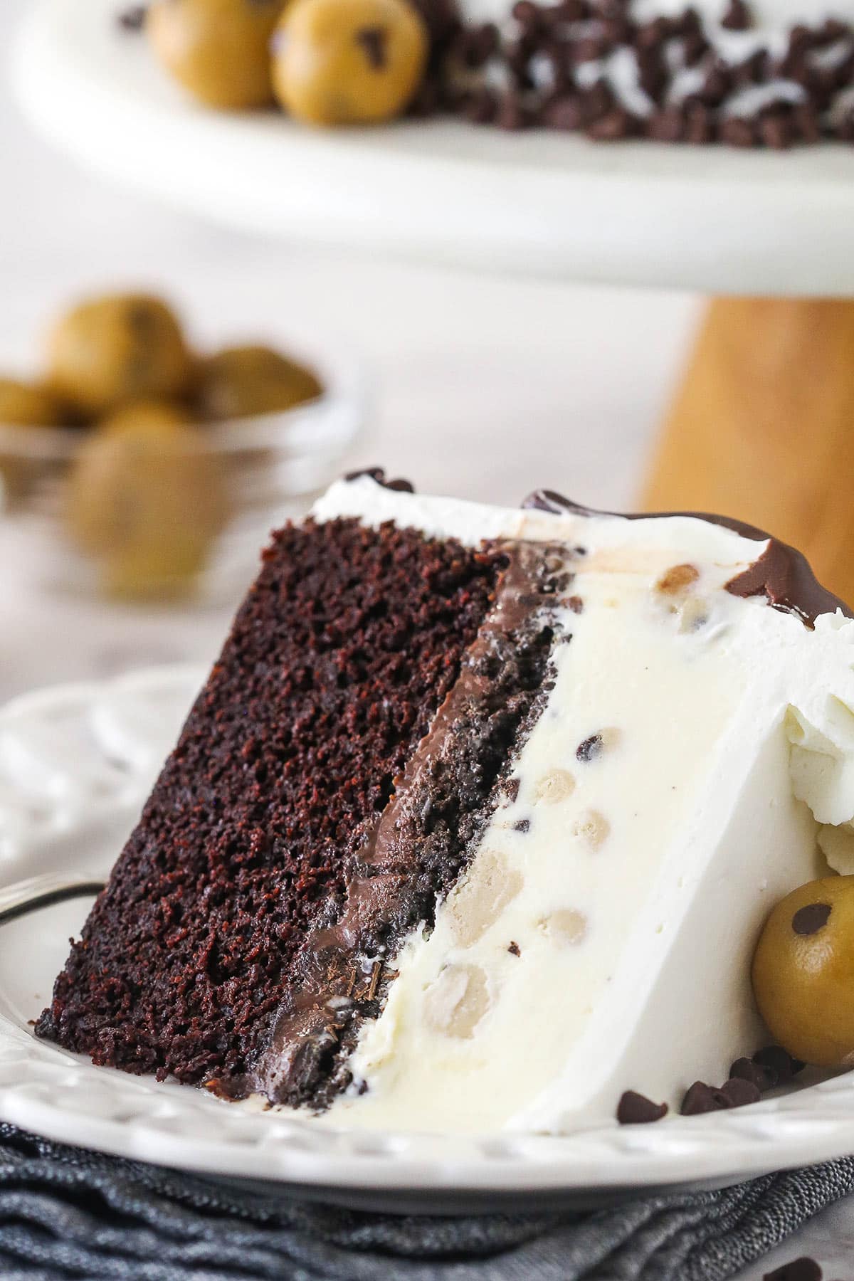 Chocolate cake, ice cream, fudgy chocolate, cookie crunchies, and a rich chocolate ganache make up this decadent ice cream cake. A slice of ice cream cake on a plate.