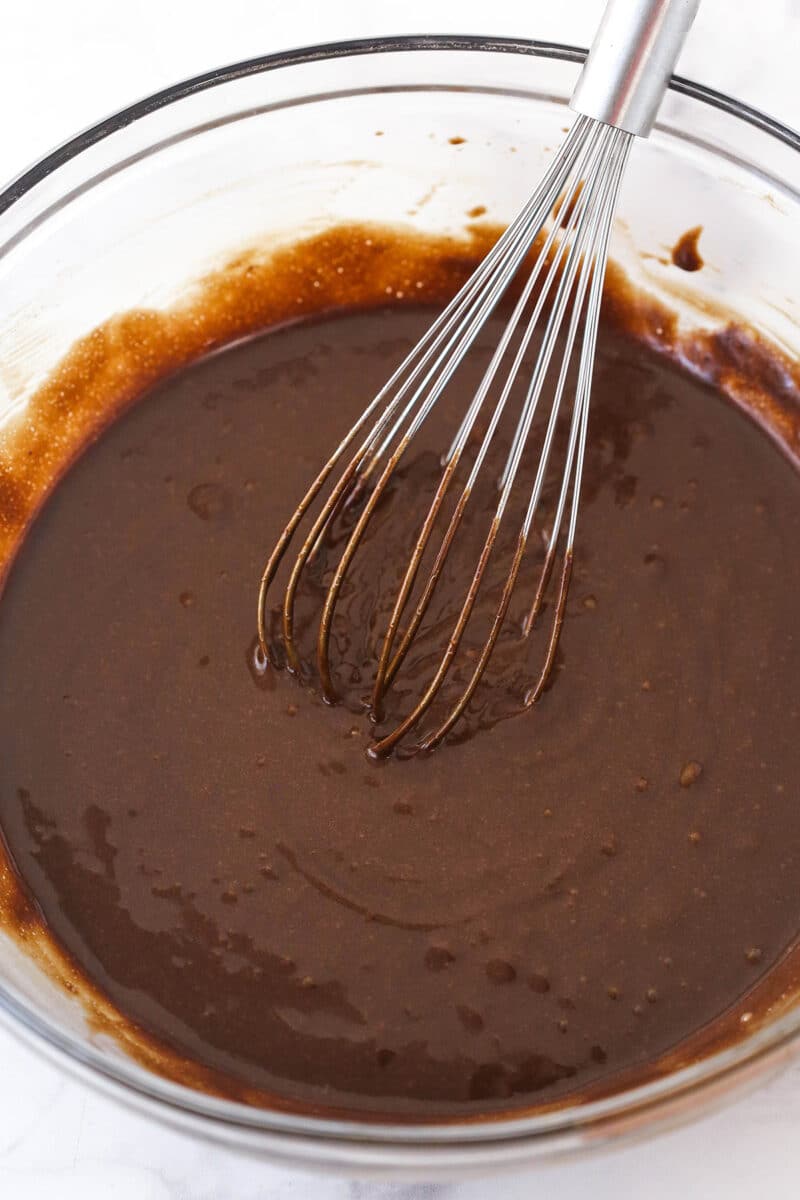 Chocolate cake batter in a mixing bowl with a whisk.