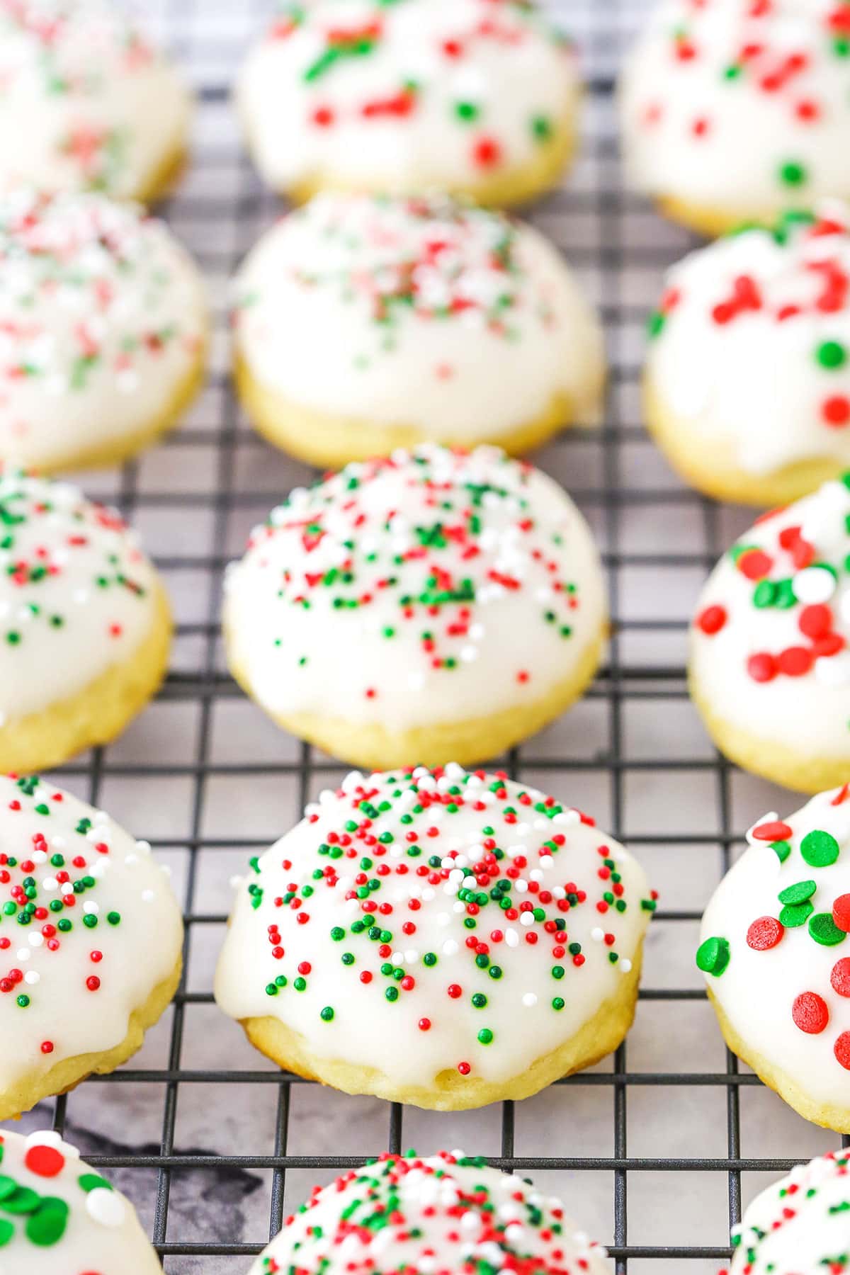 Italian Ricotta Cookies with red, green and white sprinkles spread over a metal cooling rack