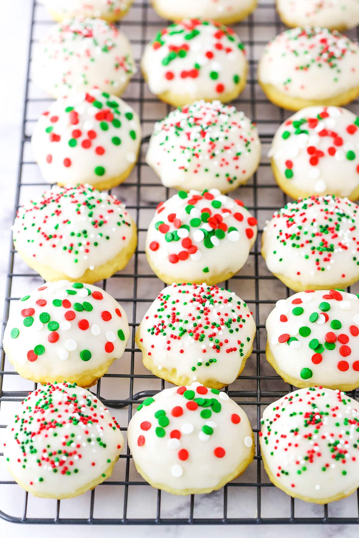 Italian Ricotta Cookies with red, green and white sprinkles spread over a metal cooling rack