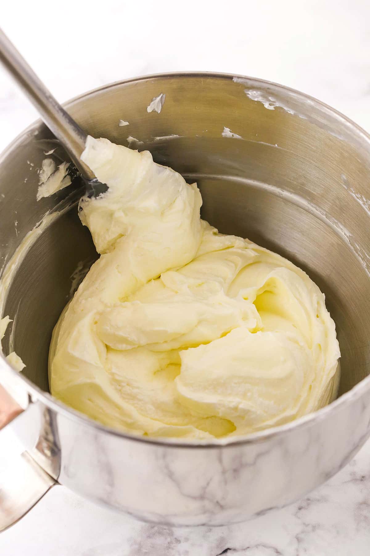 A step in making No Bake Cherry Almond Cheesecake showing folding the whipped cream into the cheesecake filling using a spatula.