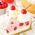 A slice of No Bake Cherry Almond Cheesecake topped with white swirls and cherries on a white plate with a fork