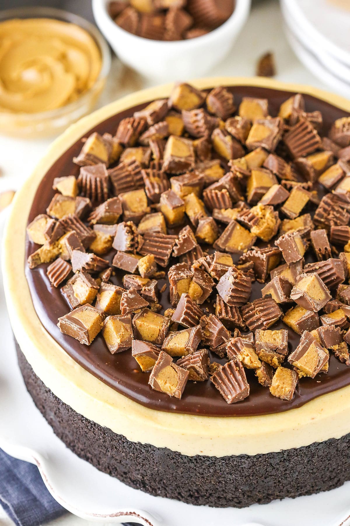 Top view of a full No Bake Reese's Peanut Butter Cheesecake topped with cut Reese's Peanut Butter Cups on a white cake stand