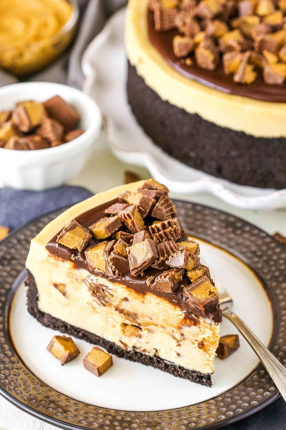 A slice of No Bake Reese's Peanut Butter Cheesecake with a fork on a white and grey plate