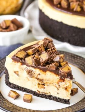A slice of No Bake Reese's Peanut Butter Cheesecake with a fork on a white and grey plate.