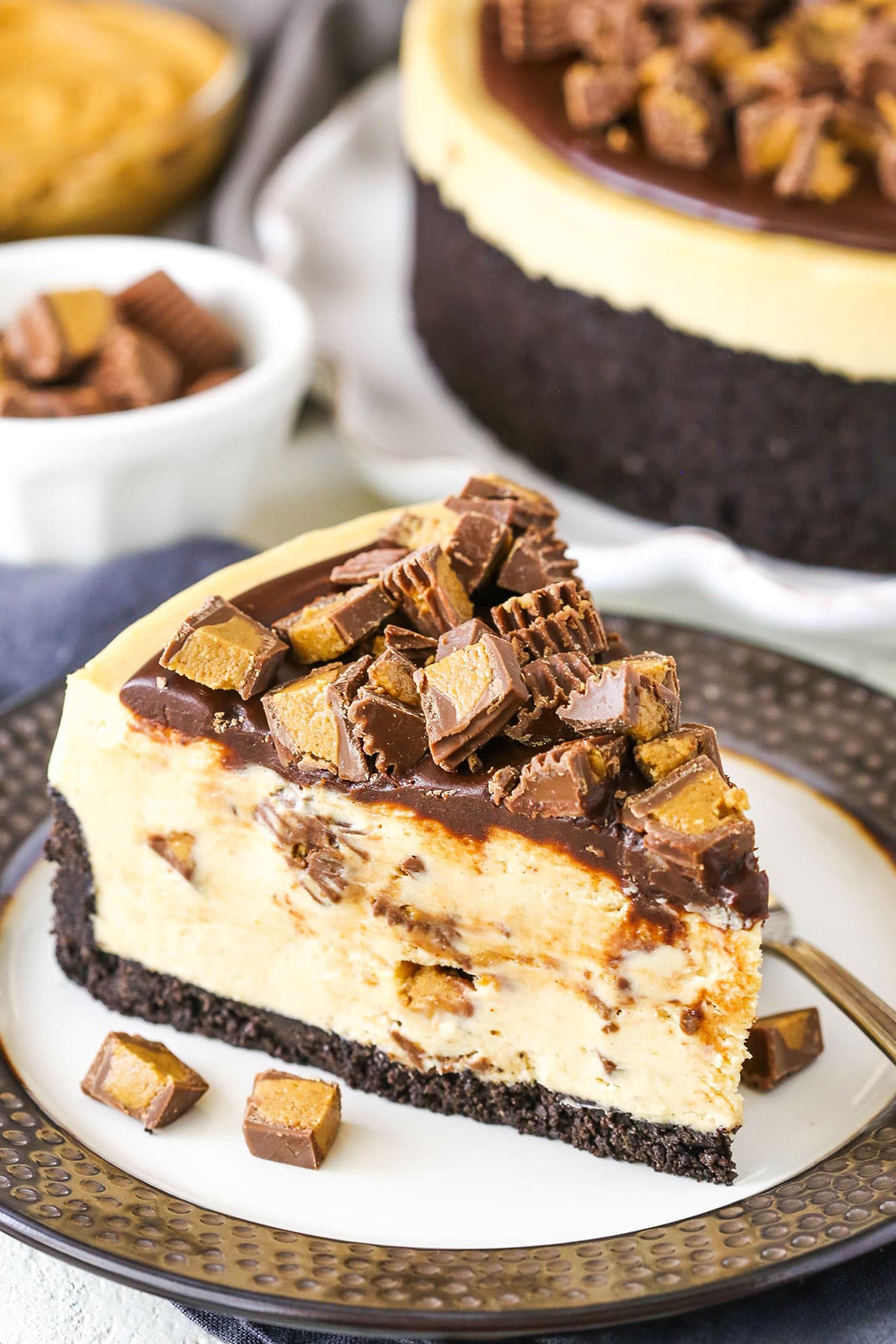 A slice of No Bake Reese's Peanut Butter Cheesecake with a fork on a white and grey plate.