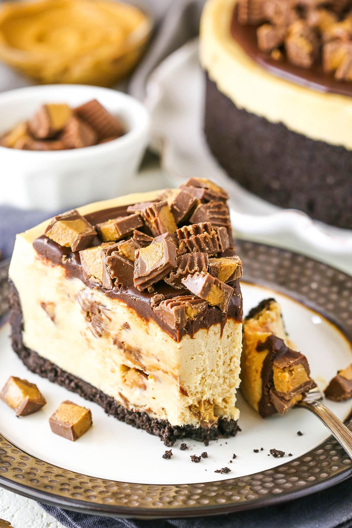 A slice of No Bake Reese's Peanut Butter Cheesecake with a bite taken out with a fork on a white and grey plate