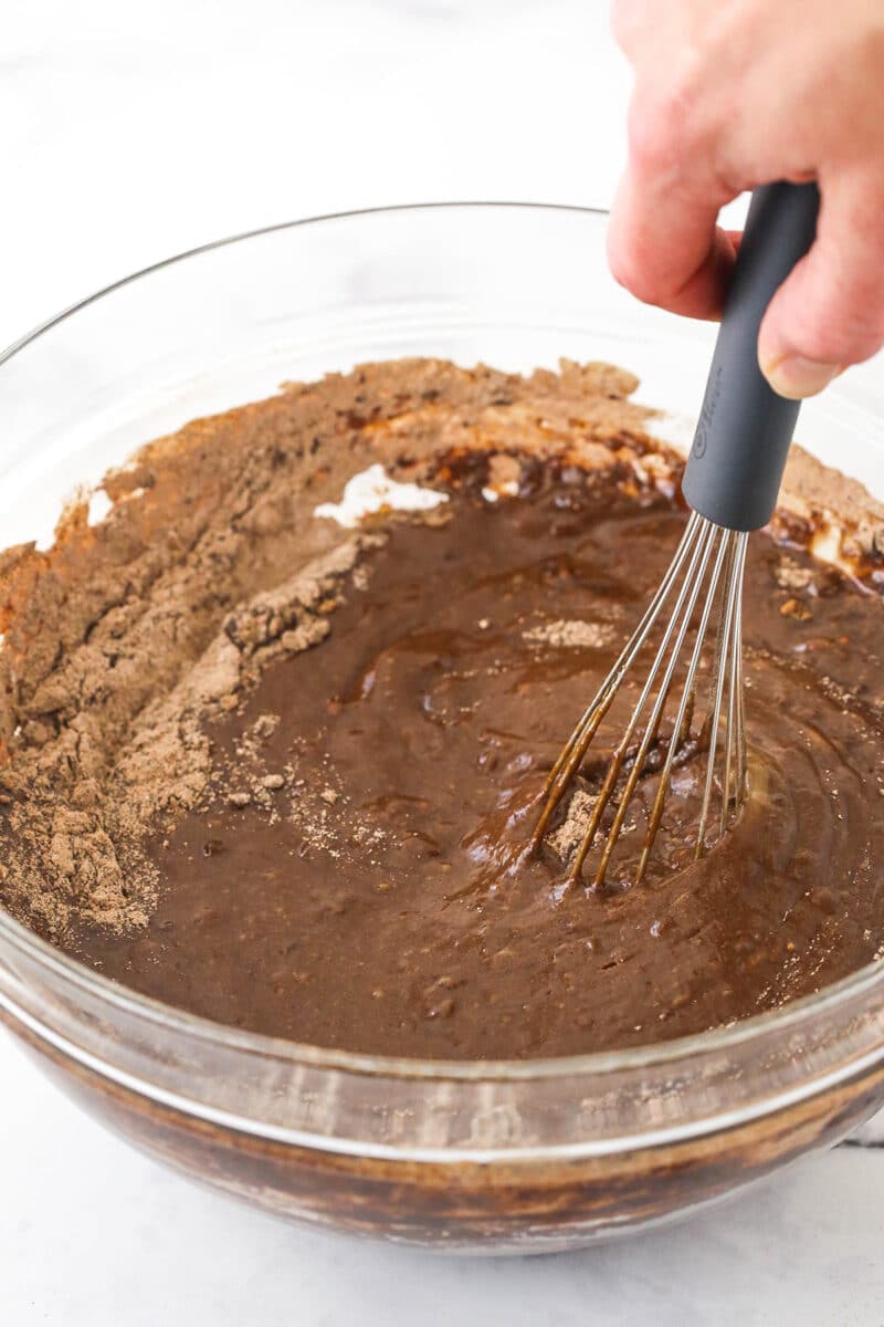 Whisking dry ingredients into chocolate cake batter.