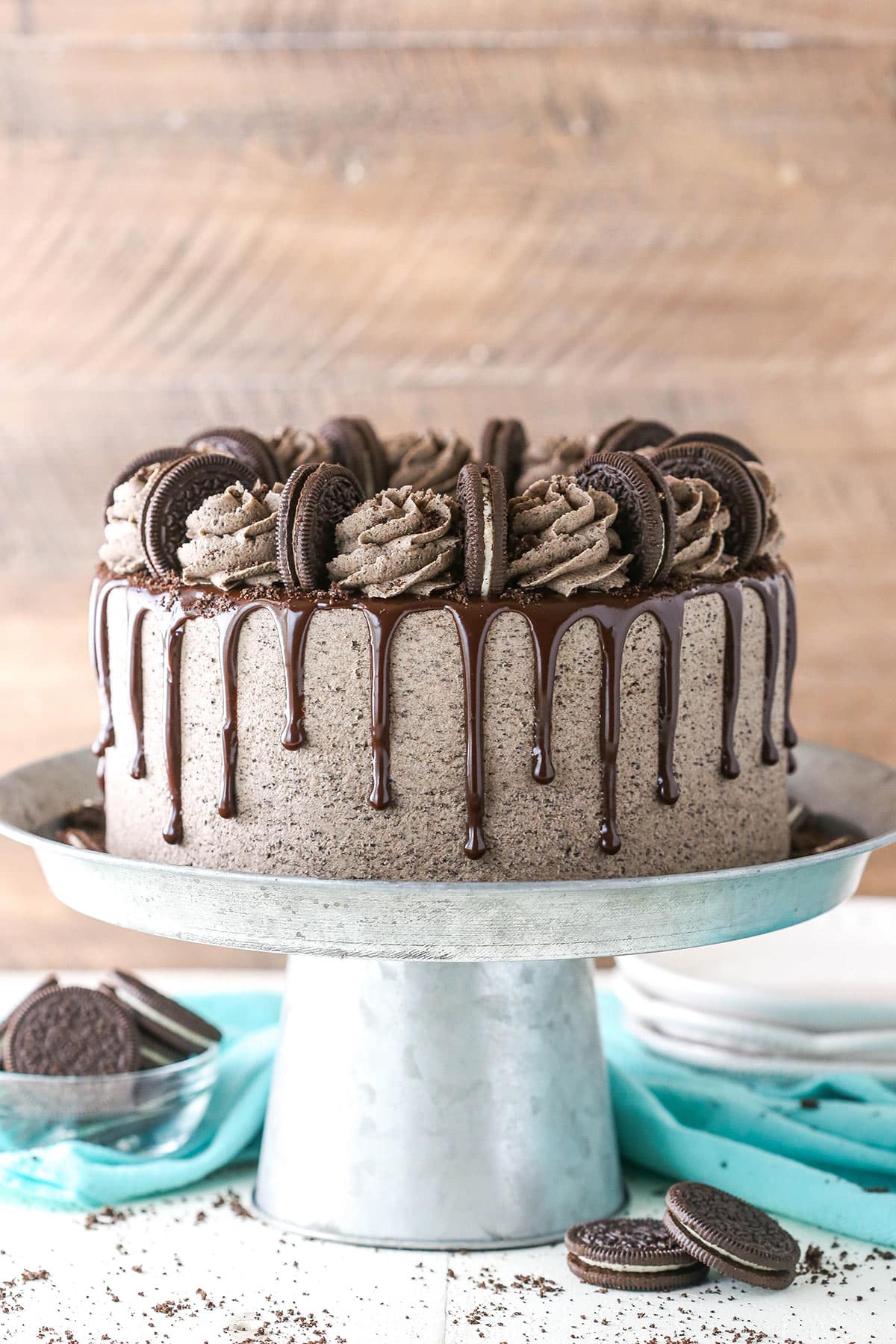 Chocolate Oreo cake on a cake stand near Oreos.