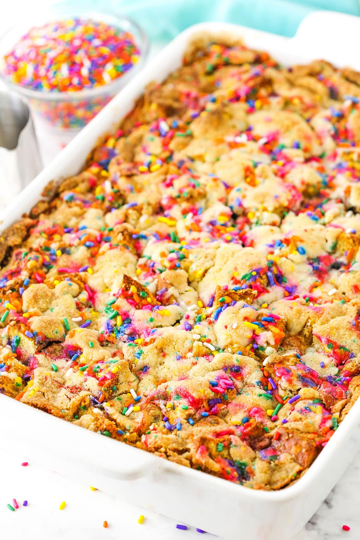 Overhead view of Overnight Birthday Cake French Toast Casserole topped with colorful sprinkles in a white platter