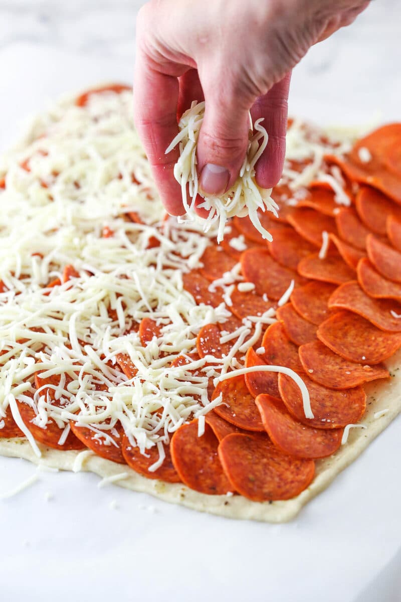 Pepperoni rolls are made up of pizza dough brushed with butter, wrapped around pepperoni and mozzarella cheese, and baked to golden brown. Sprinkling mozzarella over pepperoni layered on top of pizza dough.