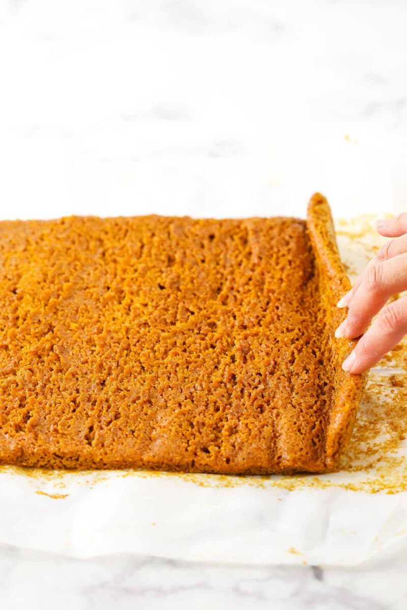 A step in making Pumpkin Roll Cake showing the unrolling of the cake and allowing it to cool before adding the filling.