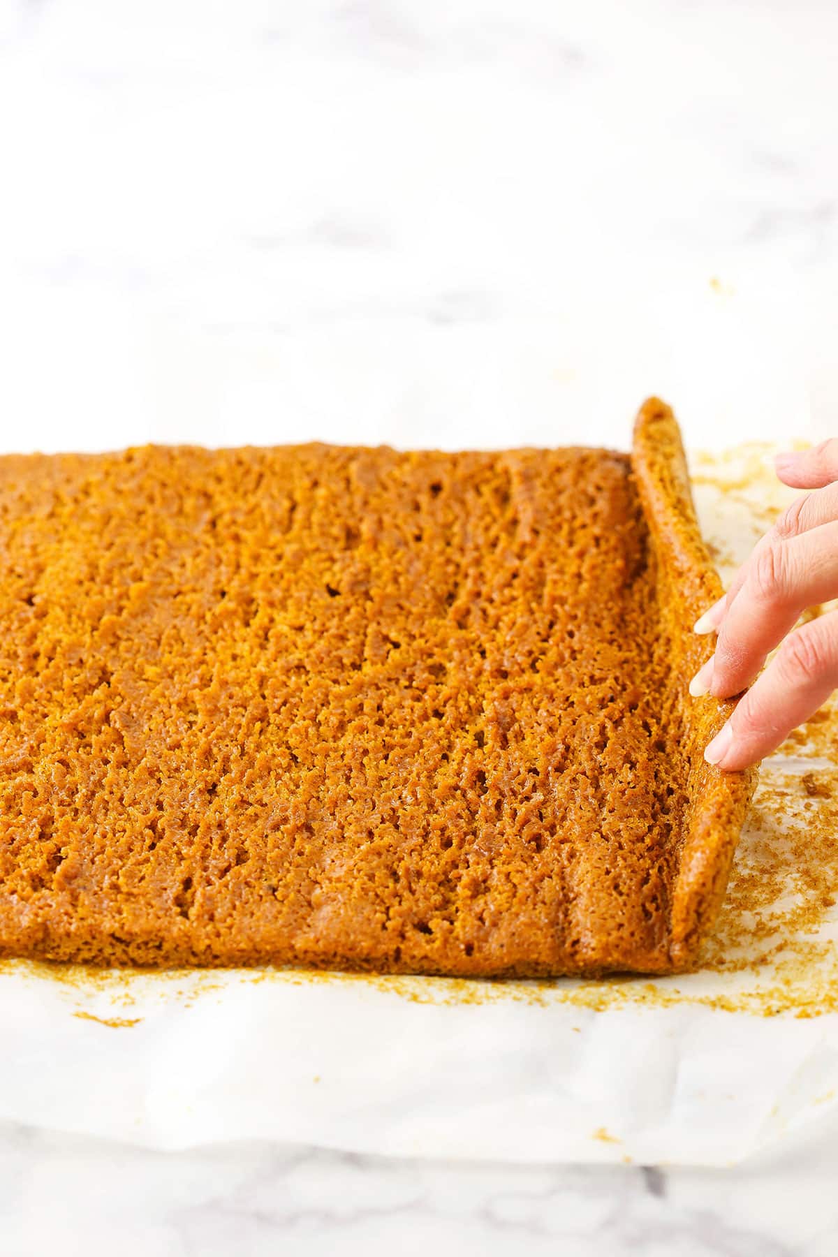 A step in making Pumpkin Roll Cake showing the unrolling of the cake and allowing it to cool before adding the filling