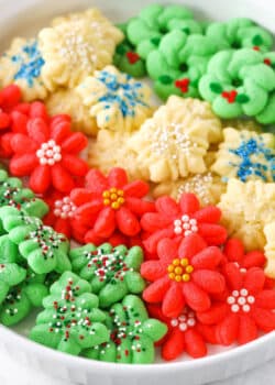 Red flower, white snowflake and green Christmas tree Spritz Cookies layered in a white cookie platter