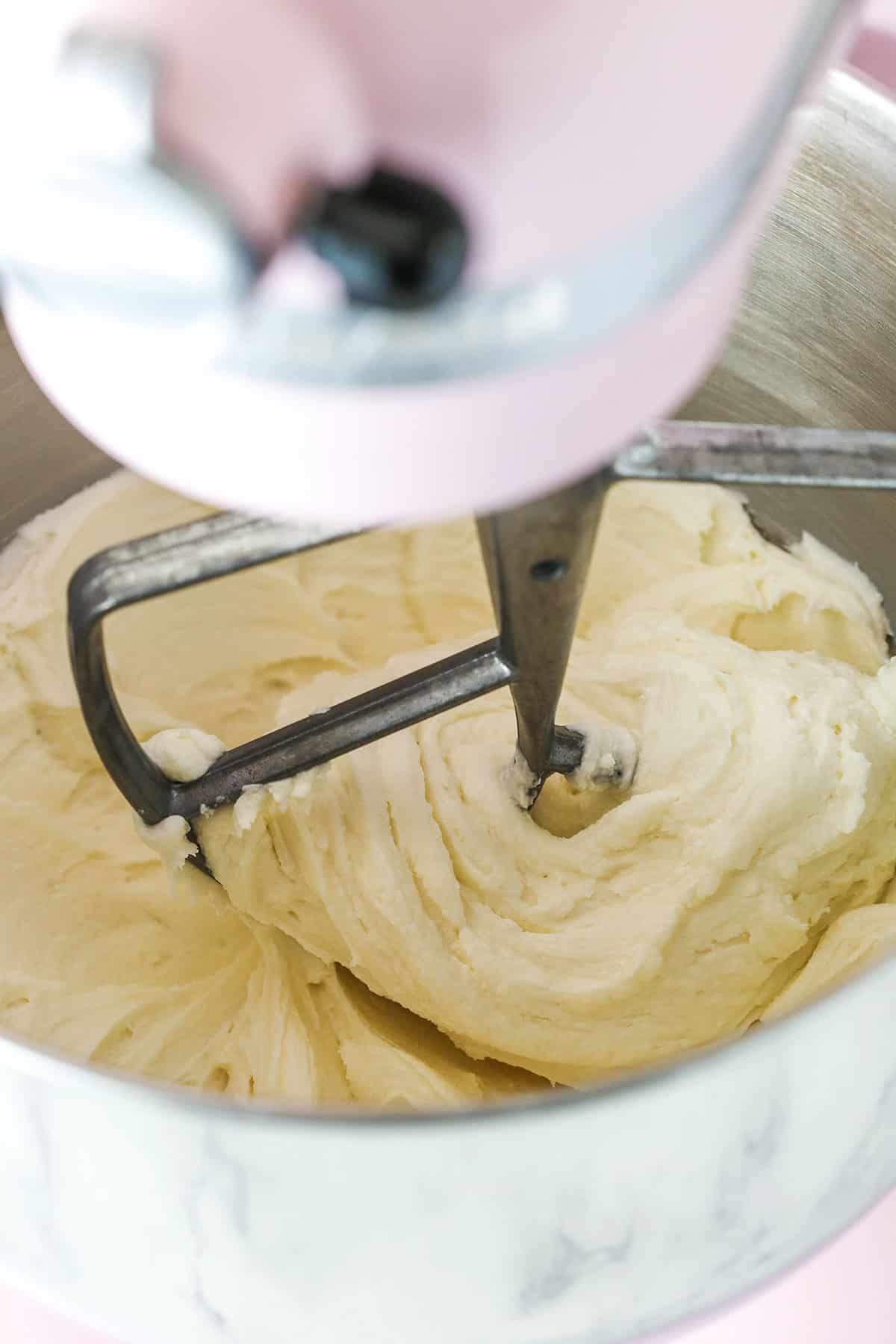Vanilla Buttercream Frosting being mixed in a large mixing bowl using a pink mixer