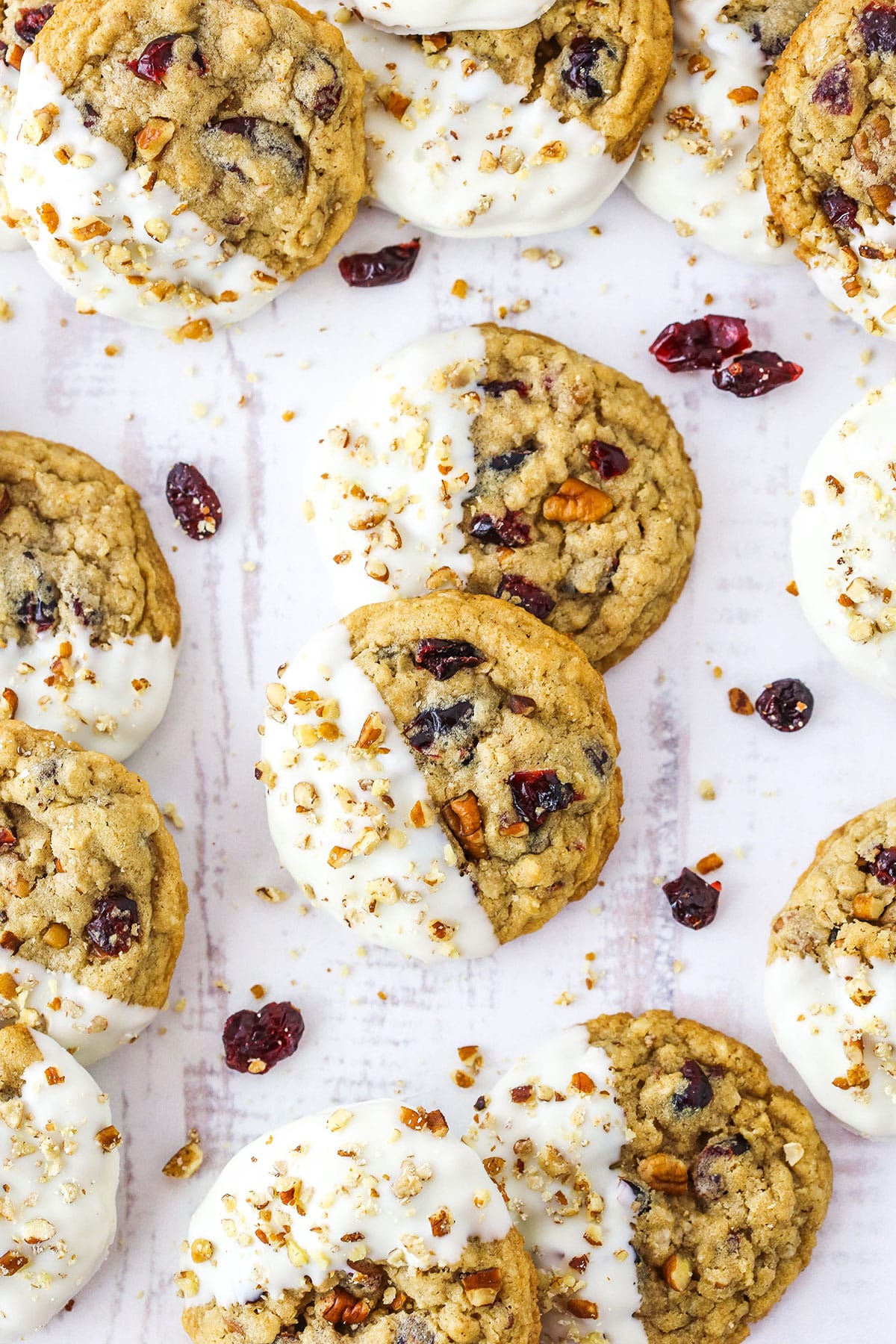 White Chocolate Dipped Cranberry Oatmeal Cookies spread out over a white table top