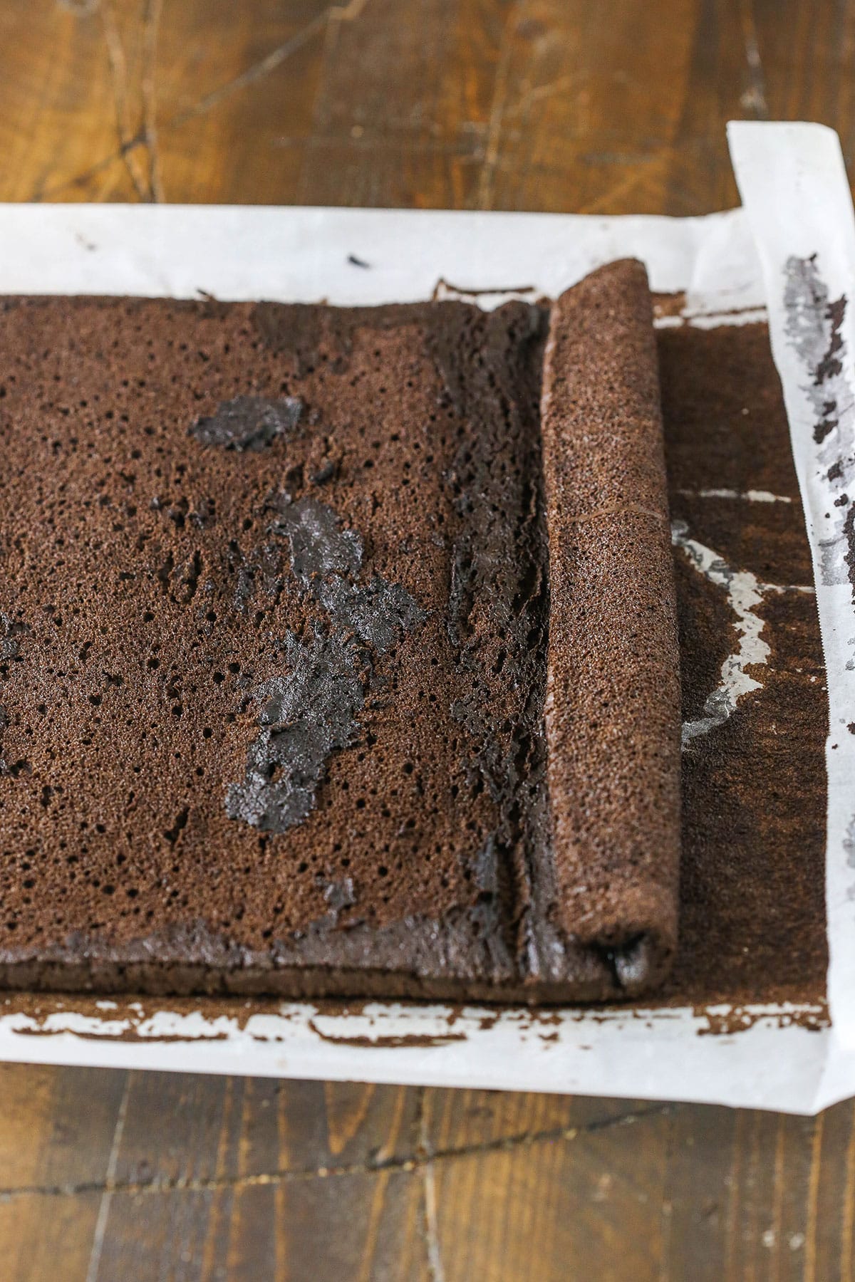 A step in making a Yule Log Cake showing the cool baked chocolate cake unrolled in preparation for adding the filling