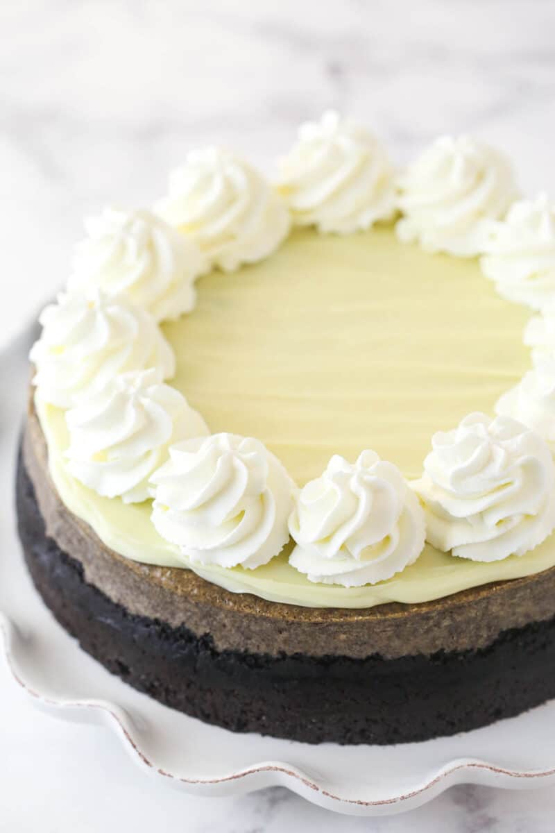 Topping Oreo cheesecake with whipped cream swirls.