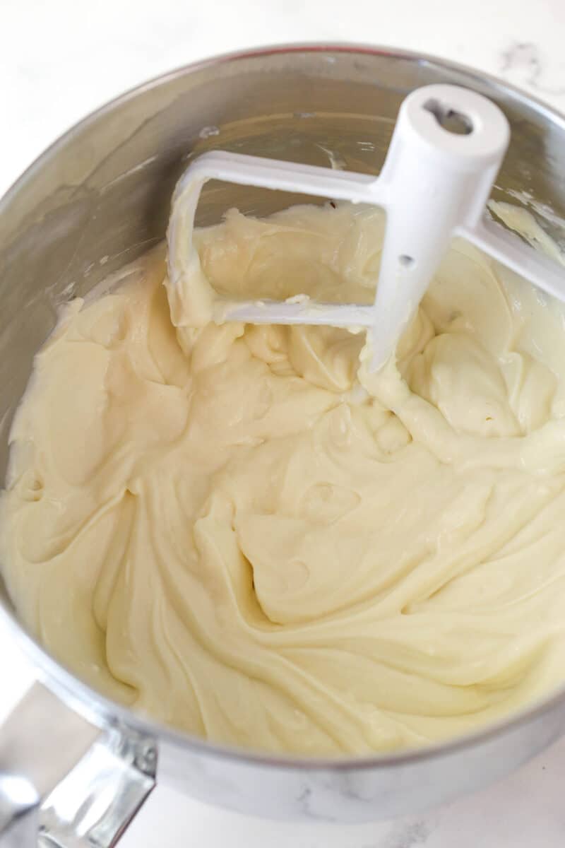 Mixing sour cream and vanilla extract into cheesecake batter.