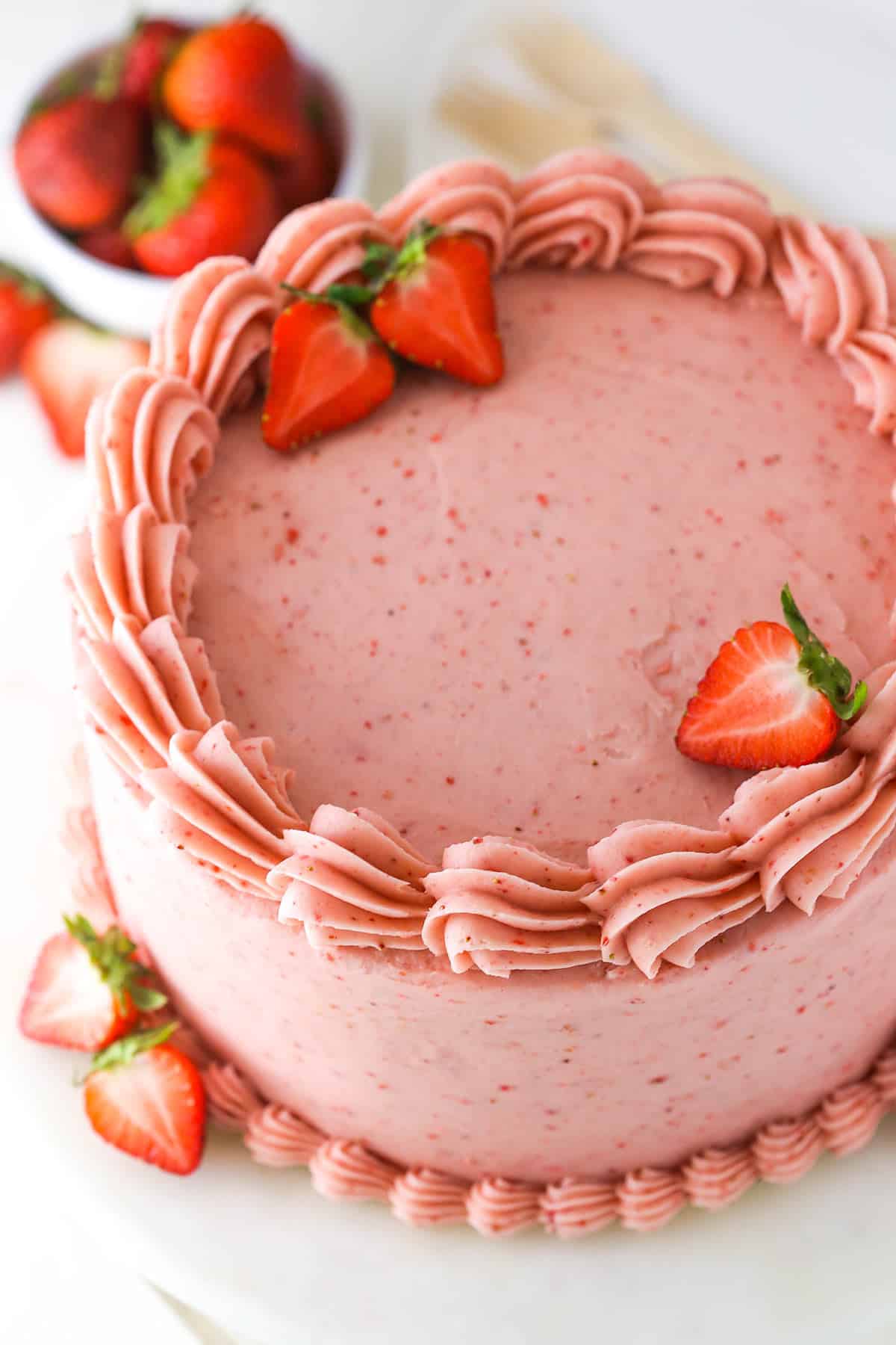 Overhead of strawberry cake near fresh strawberries.