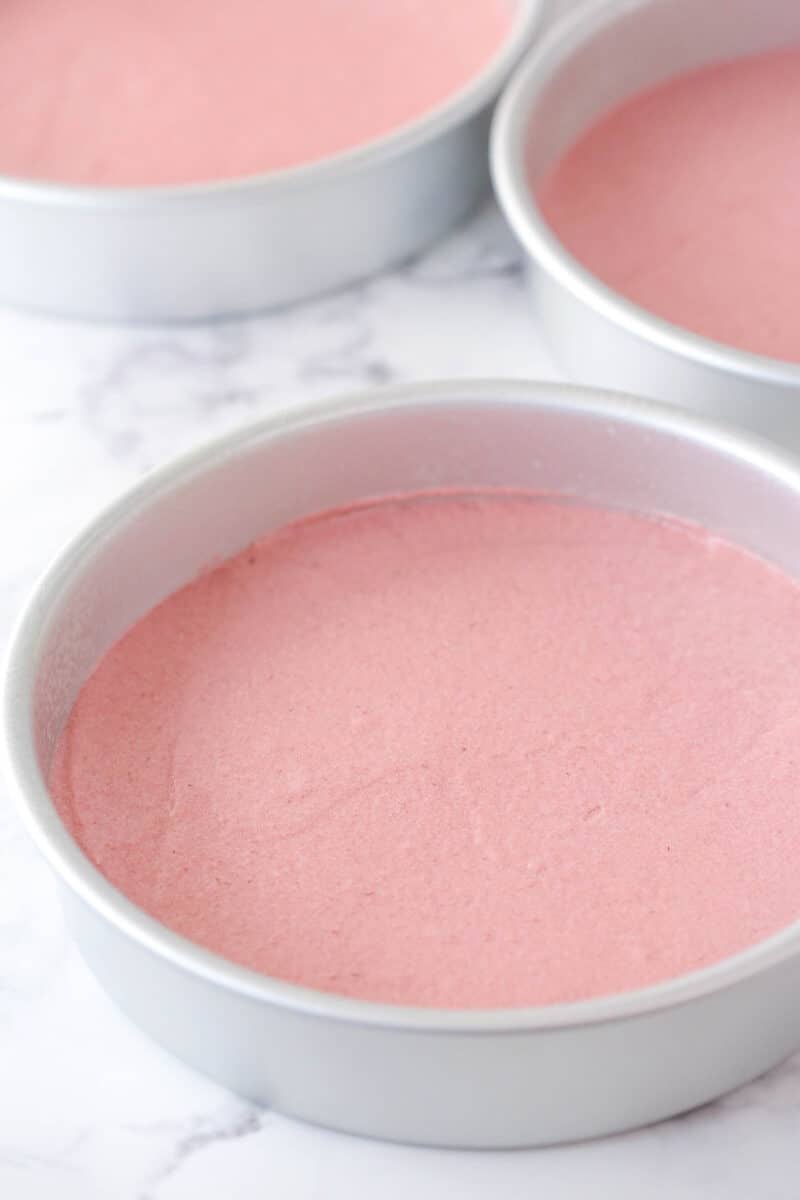 Strawberry batter in 3 cake pans ready to be baked.