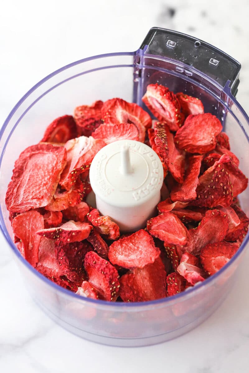 Adding freeze-dried strawberries to a food processor.