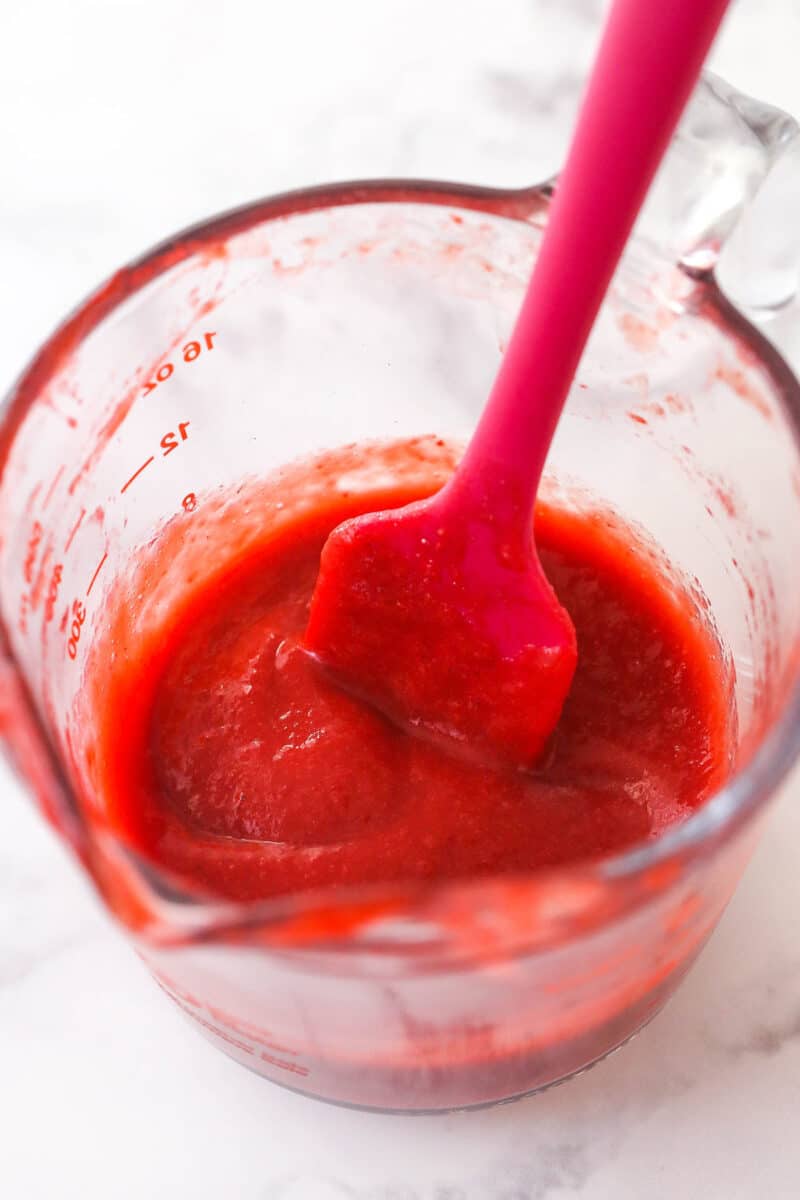 Reduced strawberry puree in a measuring cup.