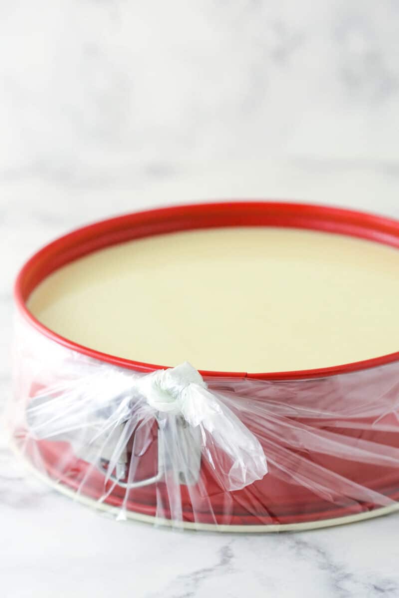 a cheesecake in a springform pan wrapped in slow cooker bag for a water bath