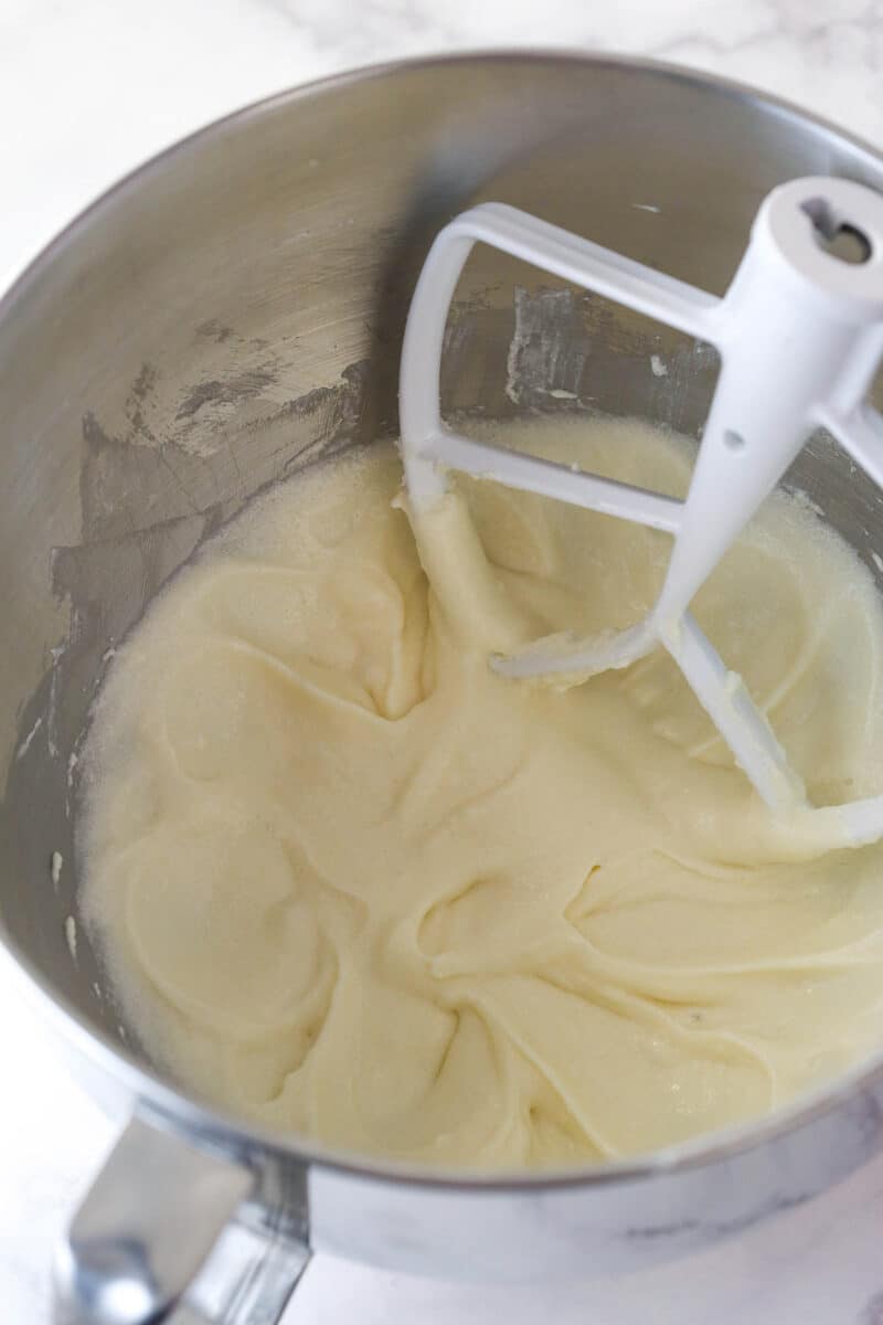 Adding sour cream and vanilla extract to creamed butter and sugar for cupcake batter.