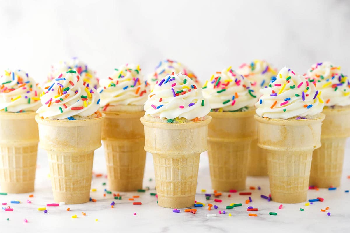 Ice cream cone cupcakes lined up on a marble surface.