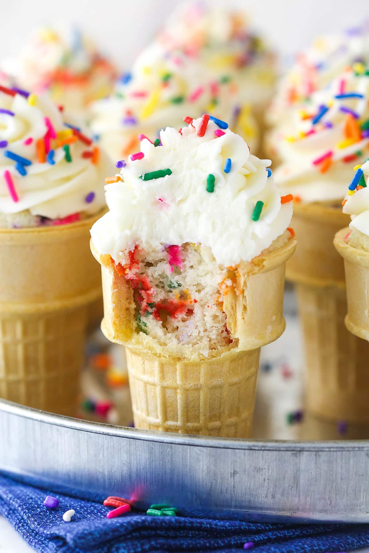 Closeup of ice cream cone cupcakes on a serving tray. One has a bite taken out of it.