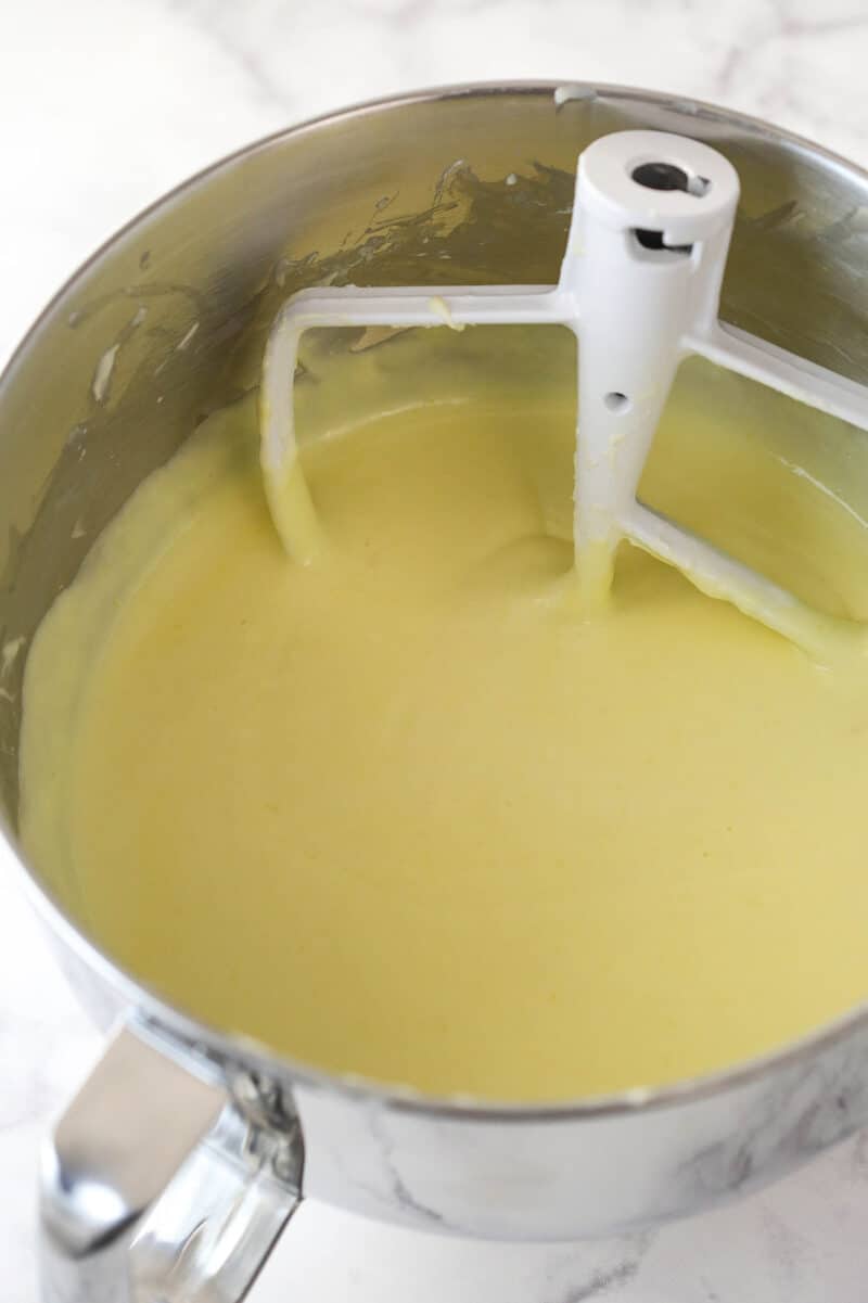 Adding eggs and egg yolks to cheesecake filling.