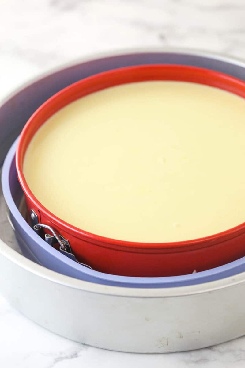 Lemon cheesecake is perfect for summer. Creamy lemon cheesecake filling is baked into sweet Graham cracker crust and topped with lemon curd. Lemon cheesecake batter in a water bath ready to be baked.