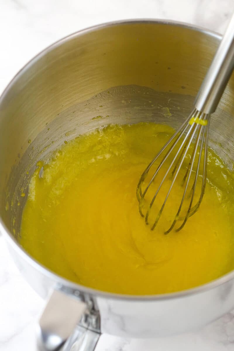Lemon cheesecake is perfect for summer. Creamy lemon cheesecake filling is baked into sweet Graham cracker crust and topped with lemon curd. Whisking lemon curd in a mixing bowl.