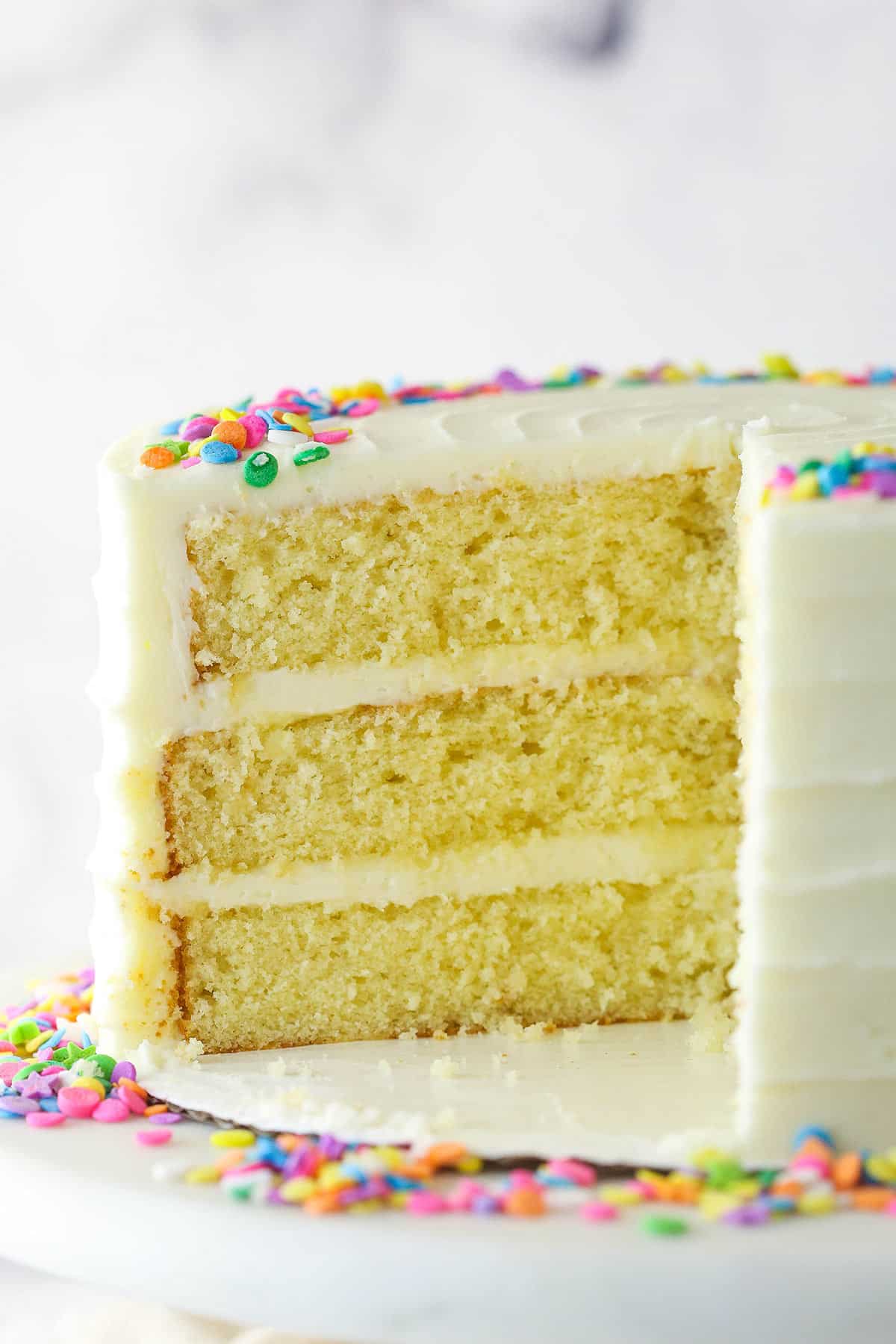 Moist vanilla layer cake with a slice taken out of it.