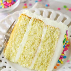 A slice of moist vanilla layer cake on a plate with a fork.