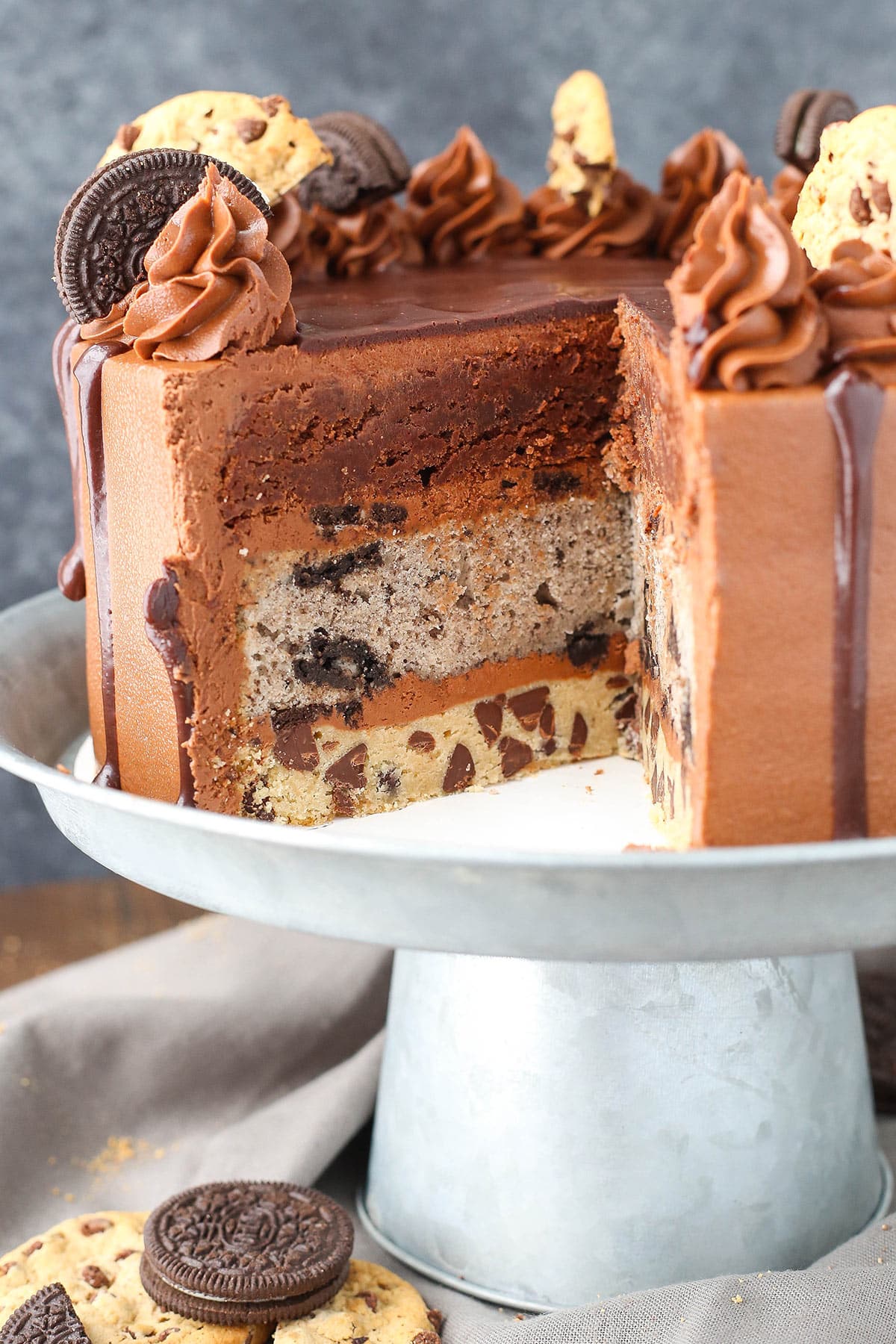 Oreo brookie cake on a cake stand with a slice taken out of it.