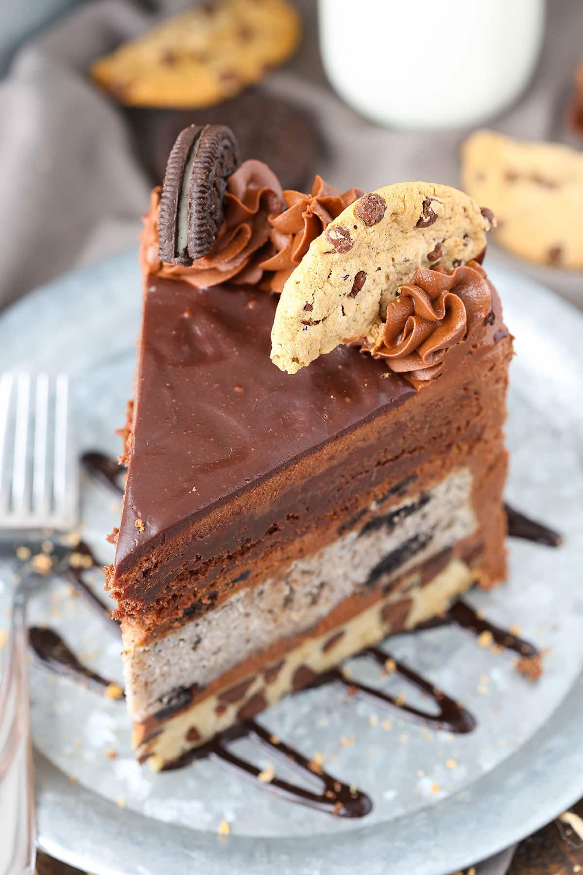 Closeup overhead of a slice of Oreo brookie layer cake on a plate with a fork.
