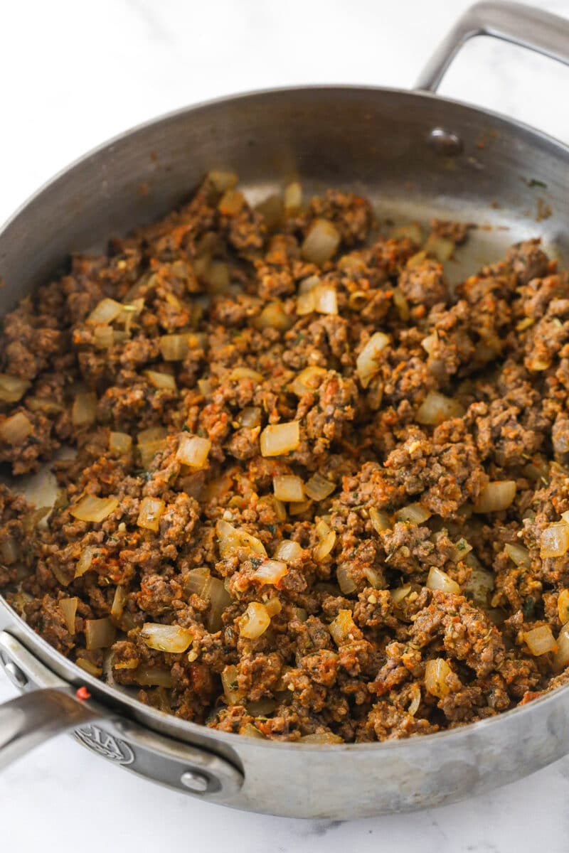 Adding Worcestershire sauce, tomato paste, flour, and garlic to cooked beef, onions, and herbs.